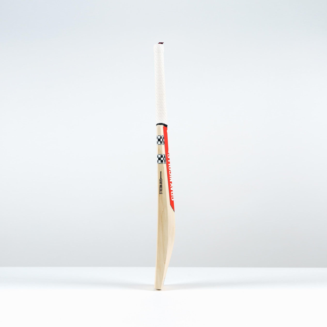 The Gray Nicolls Classic Pro Performance SH Cricket Bat 2026 features a large edge profile, white handle, red and black accents, and a checkered design, standing upright on a white surface against a light background.