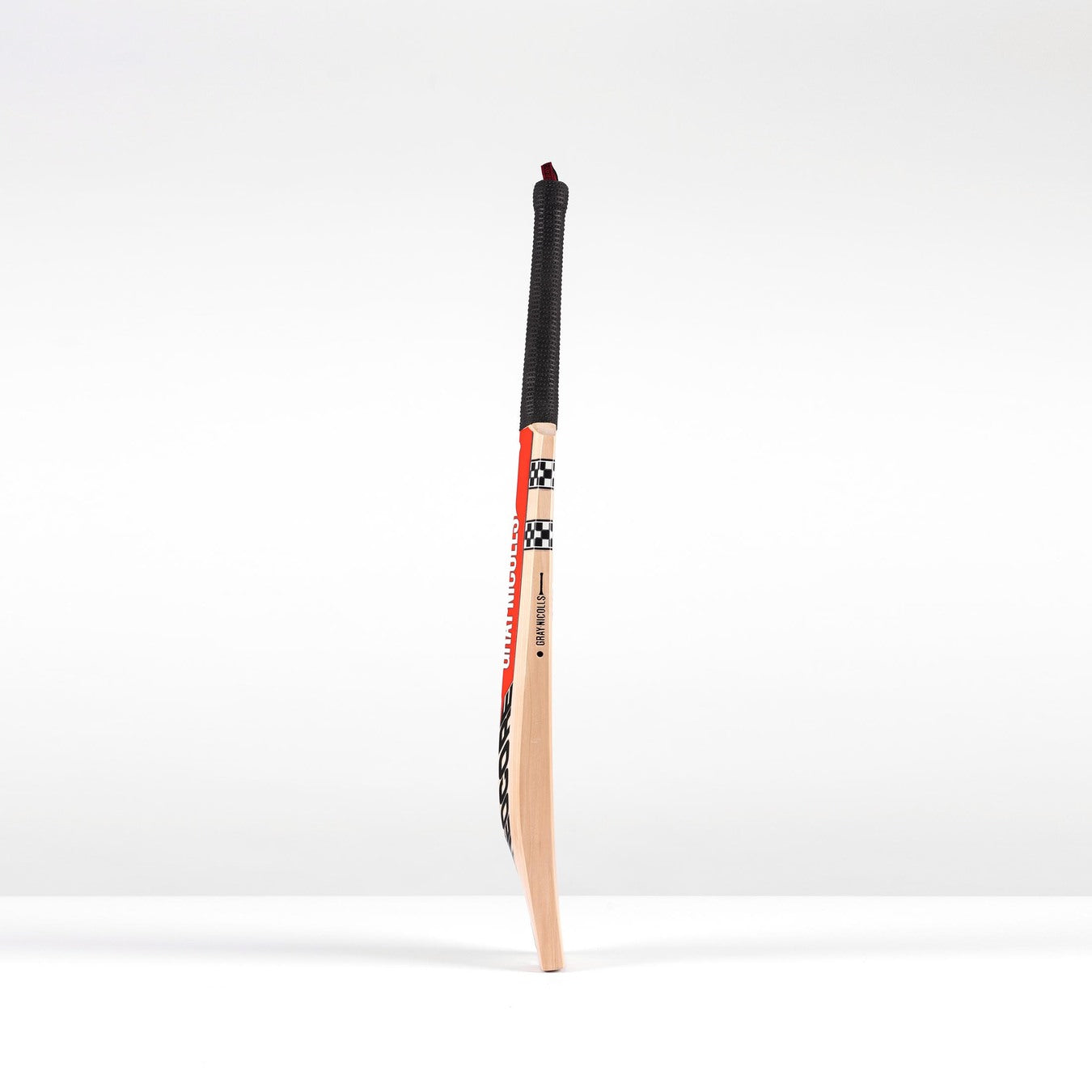 The Gray Nicolls Neocore 500 Harrow Cricket Bat 2026 stands upright, showcasing a black grip and red, black, and white Pro Shape design accents with NEOCORE technology against a white background.