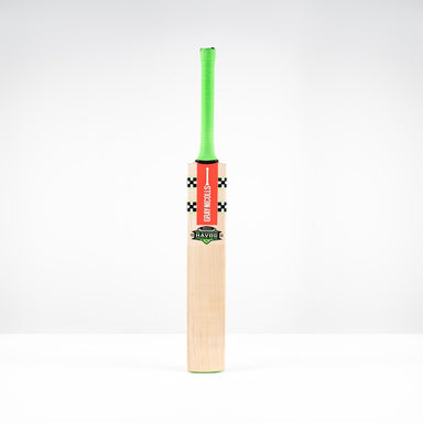The Gray Nicolls Havoc 1.3 GN550 Junior Cricket Bat 2026, featuring a light blade, green handle, and red front branding, stands upright against a plain white background.