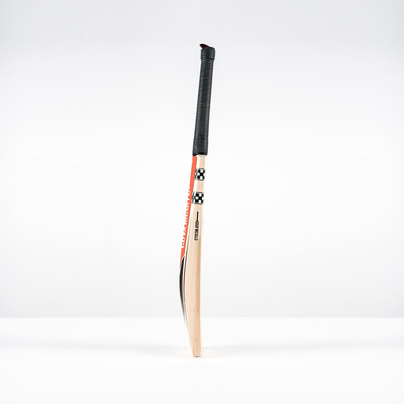 The Gray Nicolls Imperia 1.0 600 Giant SH 2026 cricket bat, featuring a low sweet spot, black grip, and red, black, and white design accents, stands upright on a plain white surface with a simple white background.
