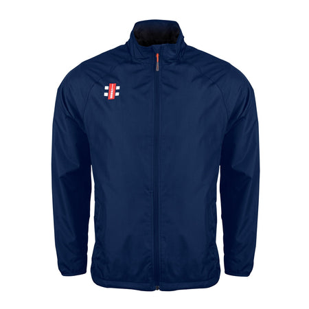 The Gray Nicolls Bushley CC Velocity Rain Jacket is a navy blue, lightweight training jacket with a high collar, long sleeves, water-repellent finish, athletic design, and a small red and white rectangular logo on the left chest.