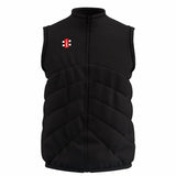 The Gray Nicolls GTS Body Warmer is a black, sleeveless puffer with a front zipper, diagonal quilted stitching, water-repellent finish, and a small rectangular red, white, and black logo on the left chest.