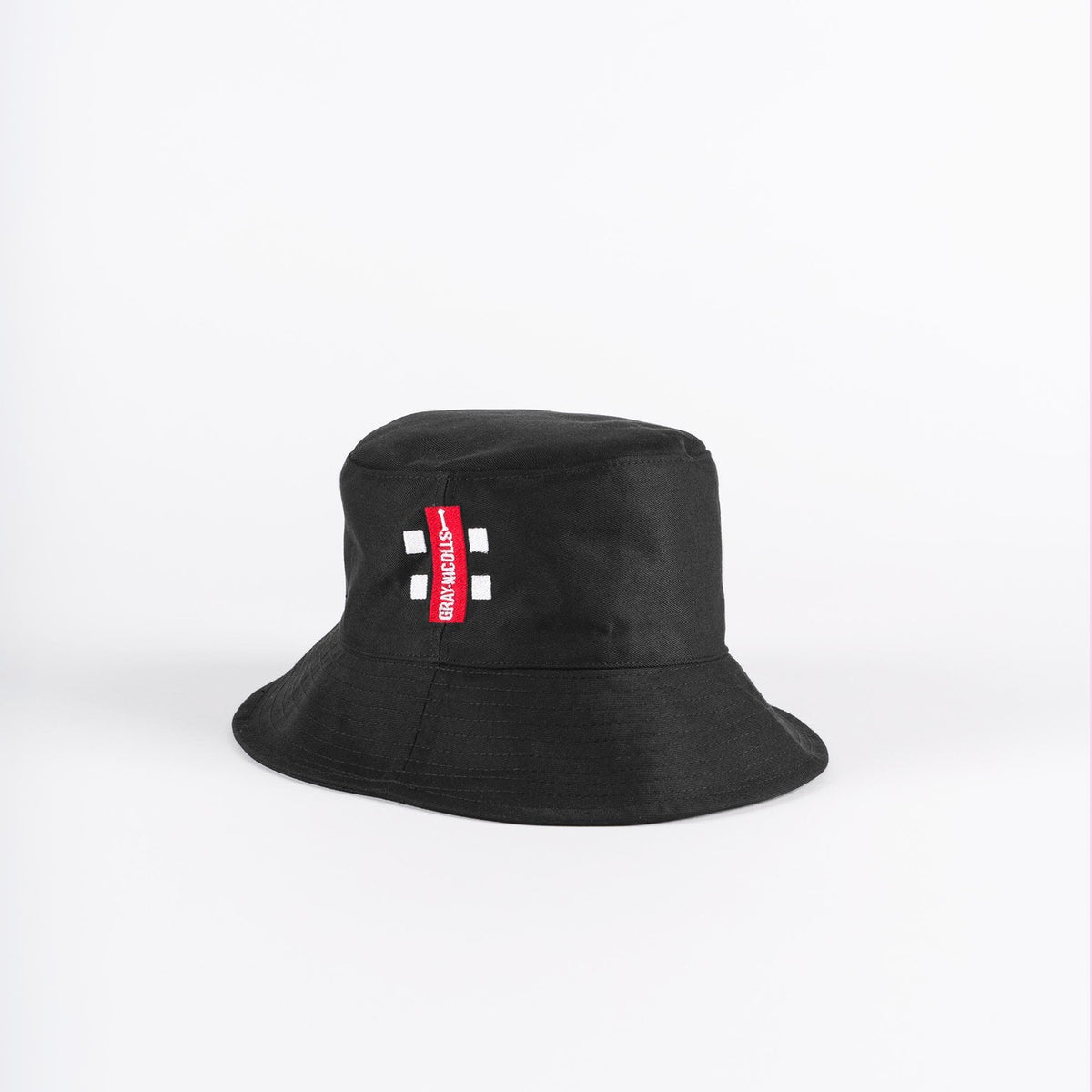 The Gray Nicolls Bucket Hat by Gray Nicolls is black with a red and white rectangular tag on the front, shown against a plain white background.