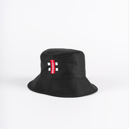The Gray Nicolls Bucket Hat by Gray Nicolls is black with a red and white rectangular tag on the front, shown against a plain white background.