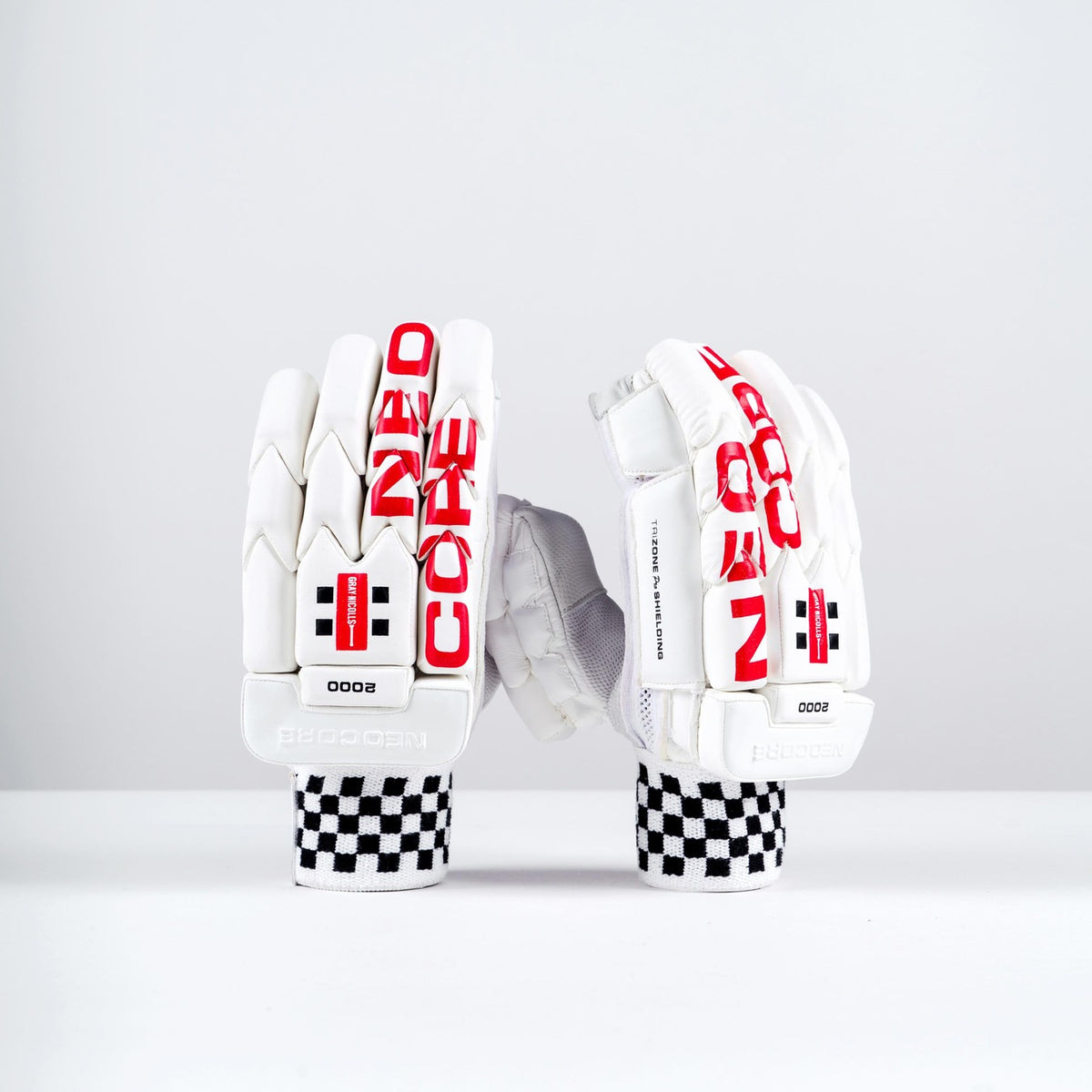 A pair of Gray Nicolls Neocore 2000 Batting Gloves 2026, white with red NEO CORE text, black checkered cuffs, and black-and-red logo details, displayed upright on a plain white background for cricket protection.
