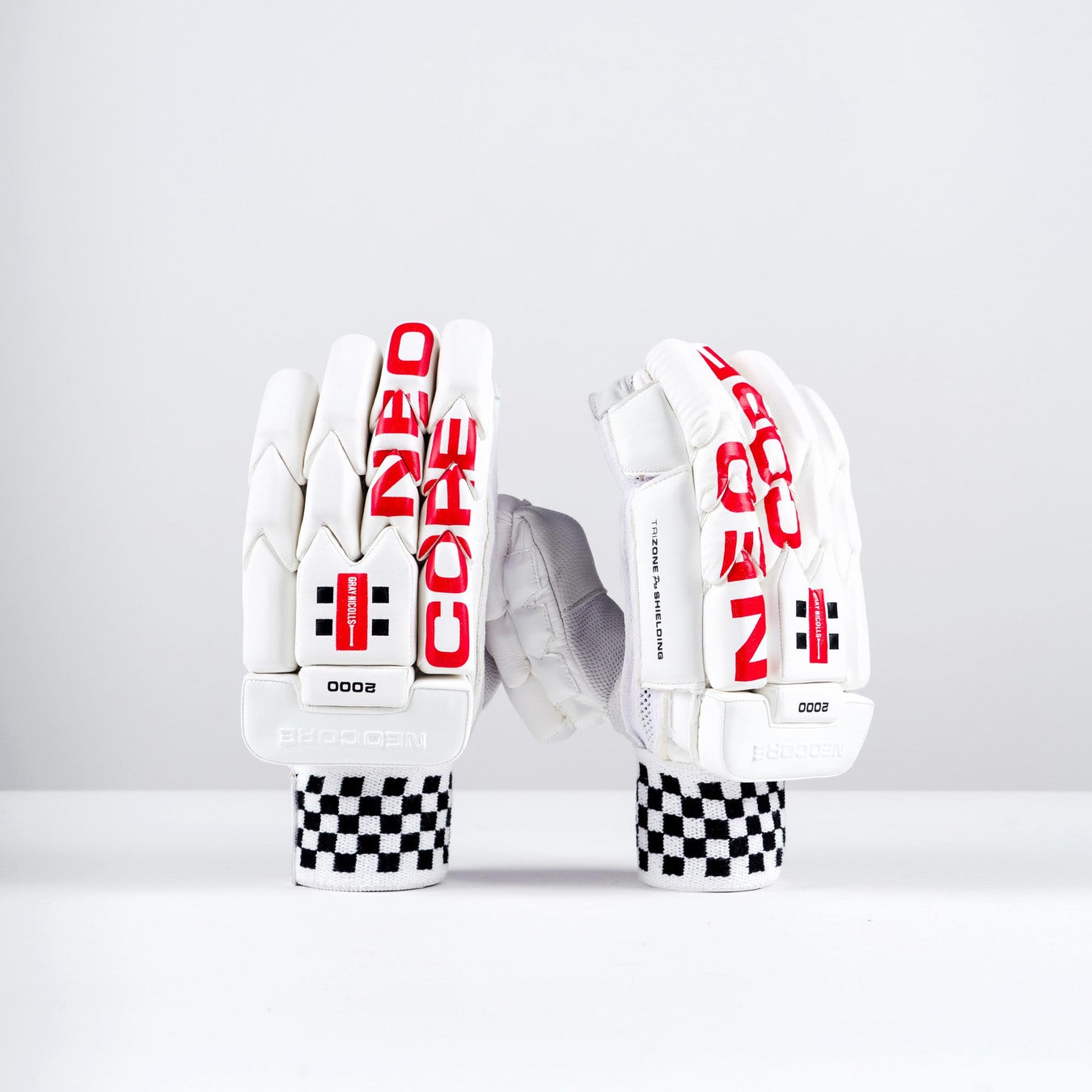 A pair of Gray Nicolls Neocore 2000 Batting Gloves 2026, white with red NEO CORE text, black checkered cuffs, and black-and-red logo details, displayed upright on a plain white background for cricket protection.