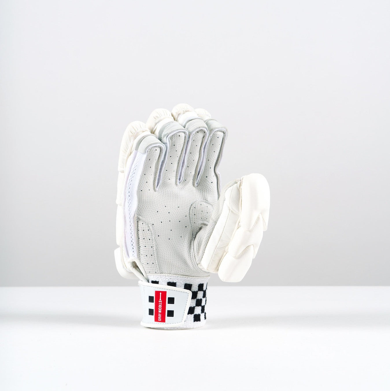 A single Gray Nicolls Neocore 2000 Batting Glove 2026 in white with black accents and extra padding stands upright; its wrist strap has a black checkered pattern and a red label.
