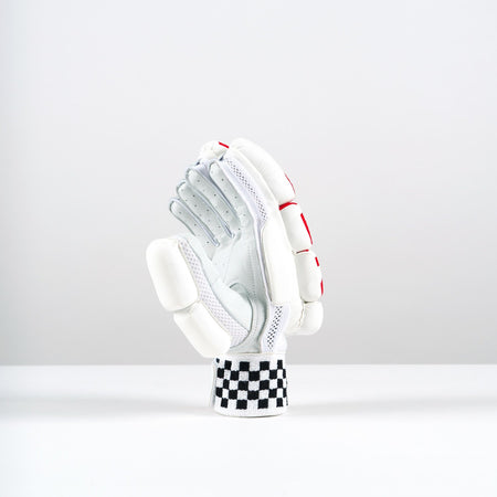 A single Gray Nicolls Neocore 500 Batting Glove stands upright on a white surface. It features tri-layer protection, padded fingers and knuckles, red accents, and a black-and-white checkered wristband against a light gray background.