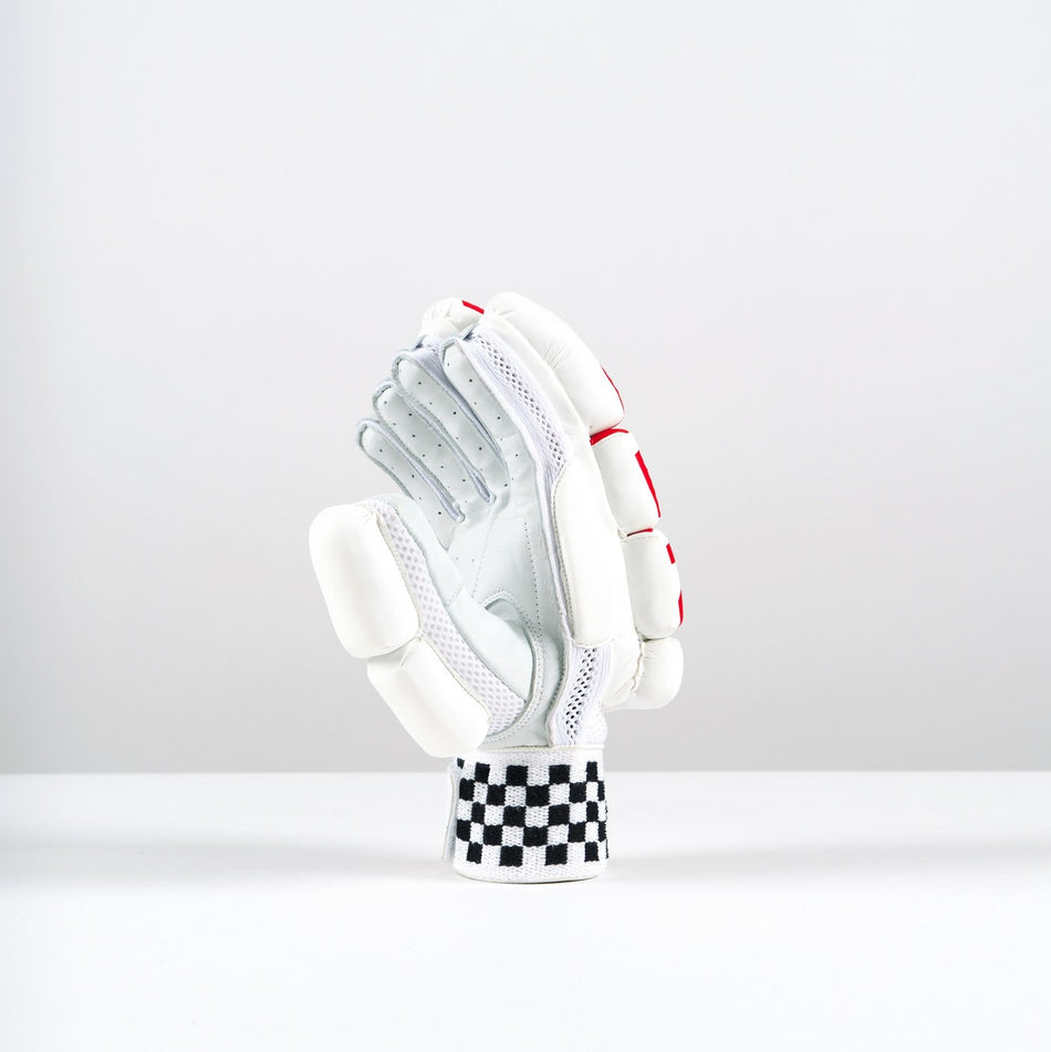 A single Gray Nicolls Neocore 500 Batting Glove stands upright on a white surface. It features tri-layer protection, padded fingers and knuckles, red accents, and a black-and-white checkered wristband against a light gray background.
