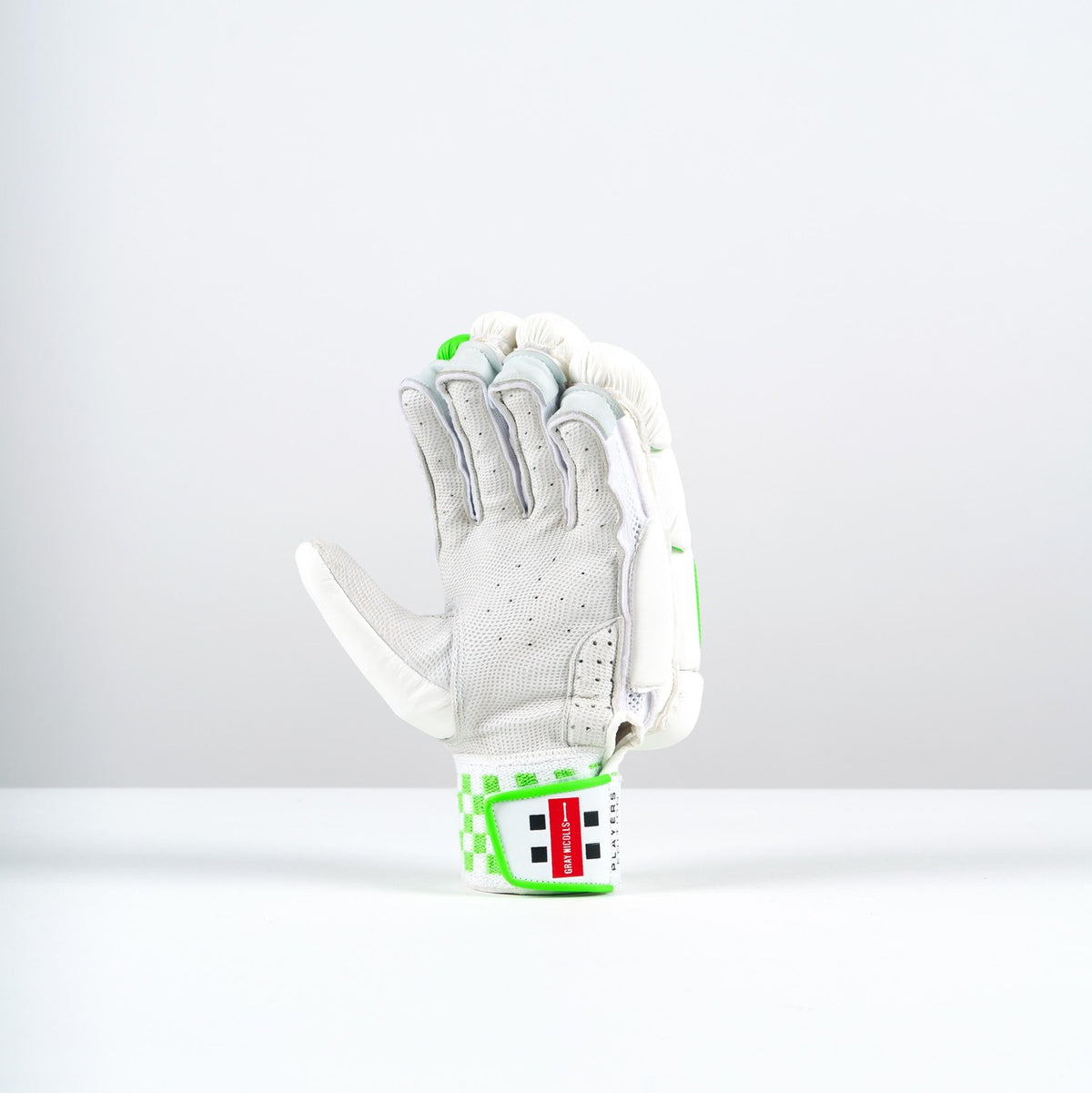 A single Gray Nicolls Classic Players Edition Batting Glove 2026 with 5-star protection and a white and gray design with green accents stands upright on a white surface against a light gray background. The wrist strap shows the red and white Gray Nicolls logo.