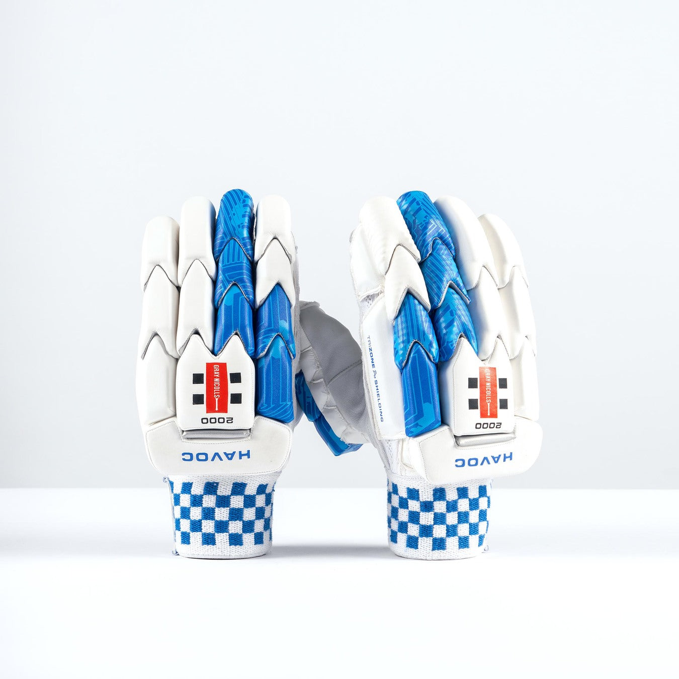 A pair of Gray Nicolls Havoc 1.0 2000 Batting Gloves 2026, white with blue accents and checkered blue-and-white wristbands reading "HAVOC," stand upright against a plain white background.