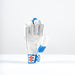 The Gray Nicolls Havoc 1.0 700 Batting Gloves 2026 stands upright, featuring white and blue colors, curved fingers for protection, perforations, blue accents, and a red-and-white patch on the wrist strap.