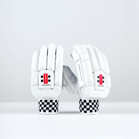 Two Gray Nicolls Classic Prestige Batting Gloves 2026 with black-and-white checkered wristbands stand upright, showing a red and black logo, "PROTECTION" print, enhanced finger protection, and leather palms for superior grip.