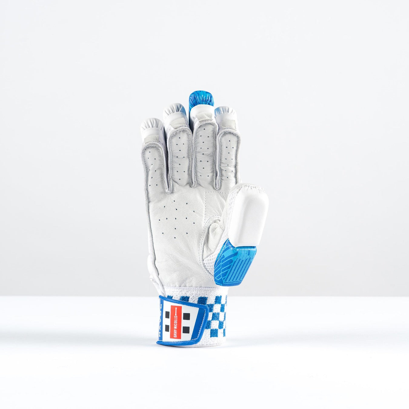The Gray Nicolls Havoc 1.0 350 Batting Gloves 2026 feature a white and blue design, padded finger protection, checkered blue trim, and a red, white, and blue wrist strap. The glove stands upright on its wrist against a plain white background.