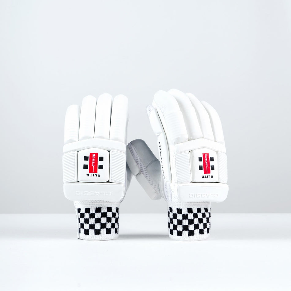 A pair of Gray Nicolls Classic Elite Batting Gloves 2026 stand upright on a white surface; featuring black-and-white checkered wristbands, these gloves offer style and performance with red and black Gray Nicolls branding.