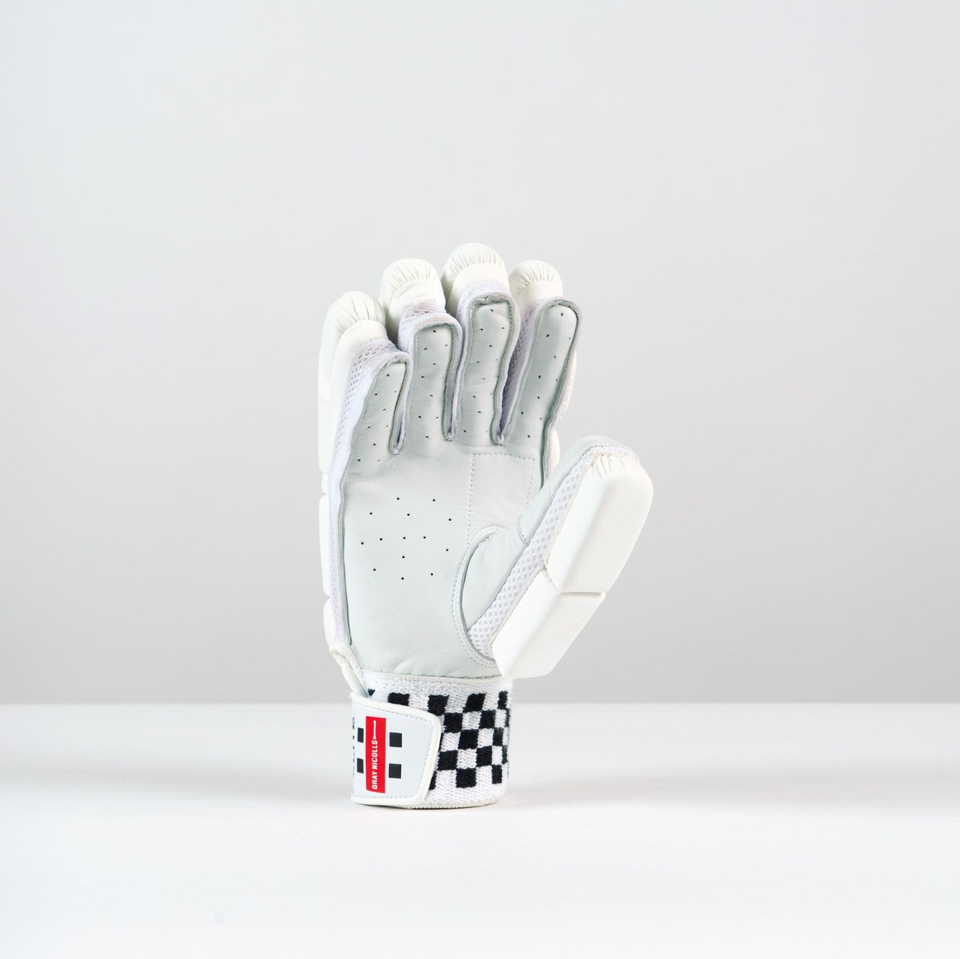 The Gray Nicolls Classic Elite Batting Gloves 2026 feature a white design with a black and white checkered strap, shown upright on a plain white surface with a light gray background—perfect for cricketers seeking elite style and protection.