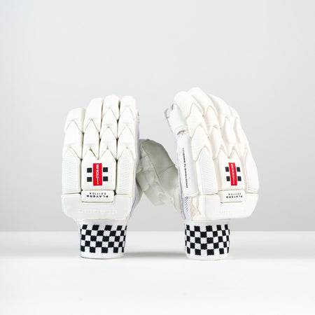 A pair of Gray Nicolls Classic Players Edition Batting Gloves 2026 in white are displayed upright on a plain white surface with black and white checkered wristbands and red labels, against a white background.