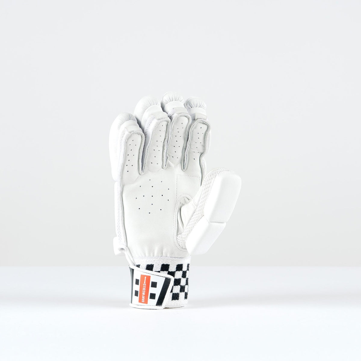 The Gray Nicolls Ultimate 500 Batting Glove 2026, in white with black checkered and red wrist strap details, stands upright on a plain background and features tri-layer protection for enhanced safety.