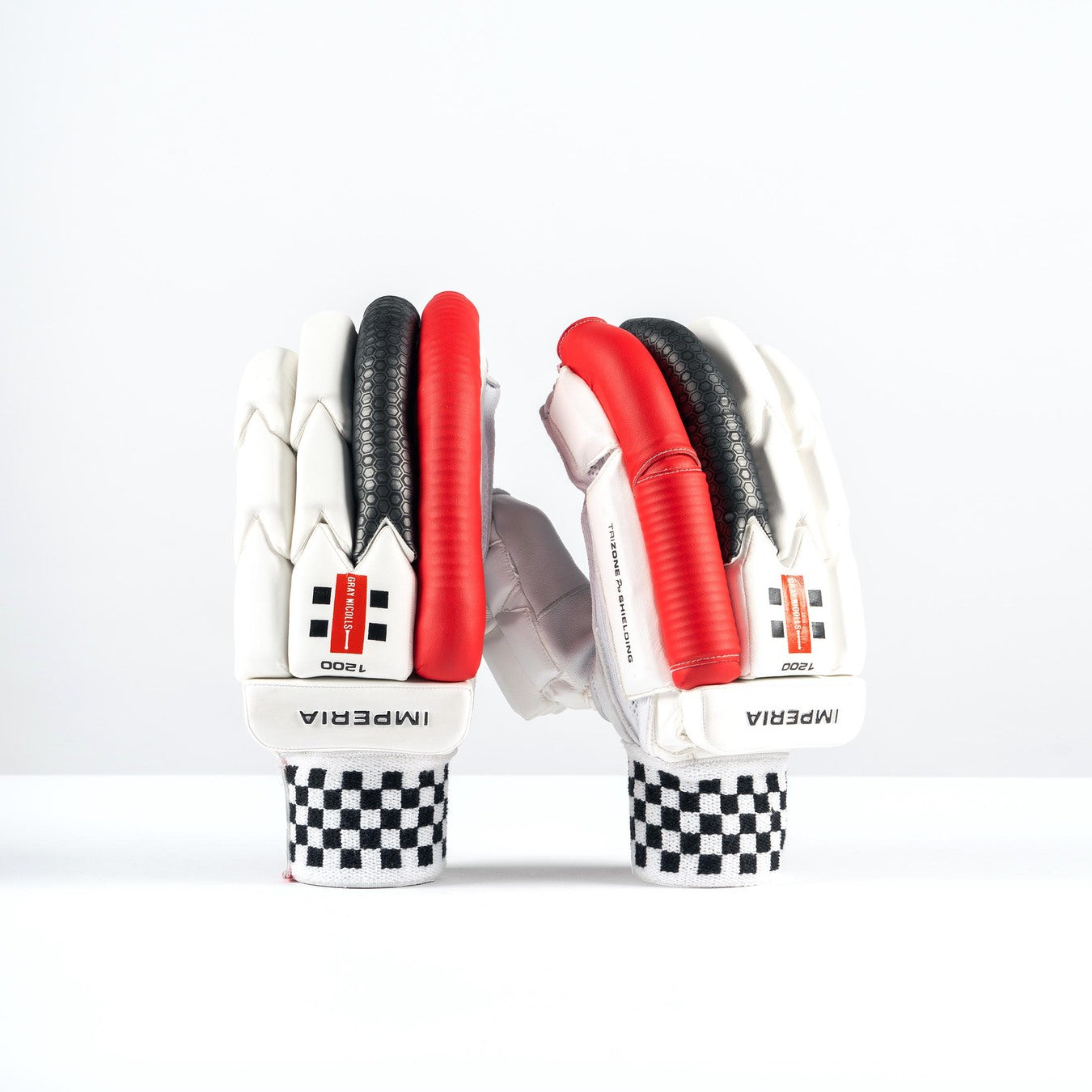 A pair of Gray Nicolls Imperia 1200 Batting Gloves 2026 in white with black and red accents stands upright on a white surface. The pro-level hybrid design features checkered cuffs and visible IMPERIA branding.