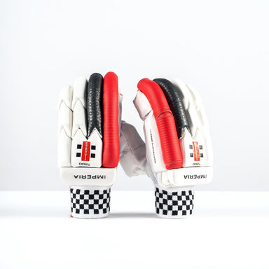 A pair of Gray Nicolls Imperia 1200 Batting Gloves 2026 in white with black and red accents stands upright on a white surface. The pro-level hybrid design features checkered cuffs and visible IMPERIA branding.