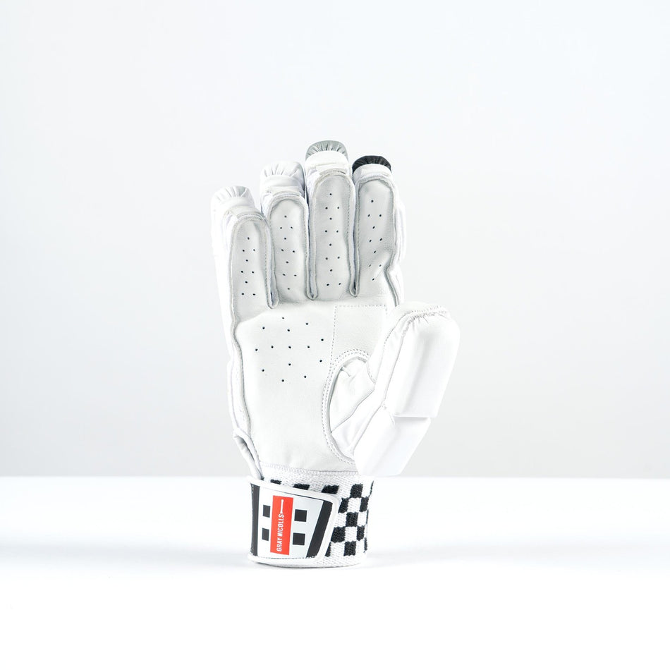 The Gray Nicolls GN500X Batting Glove 2026 is a white, lightweight glove with perforations and high-density foam padding. It stands upright on a white background, featuring a red and black wrist label with a black-and-white checkered pattern.