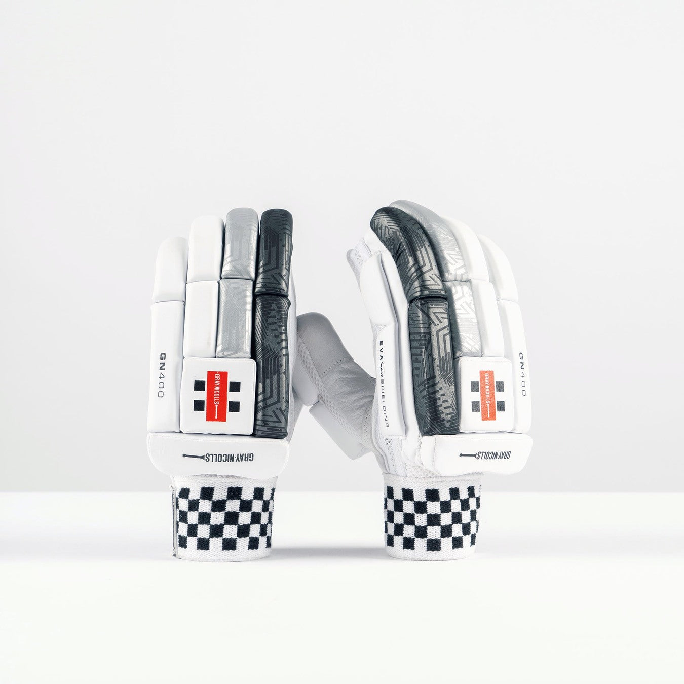 The Gray Nicolls GN400X Batting Glove 2026 features high-density foam padding, black and white checkered wristbands, white and gray padded fingers, and orange-black logo patches, shown upright against a plain white background.