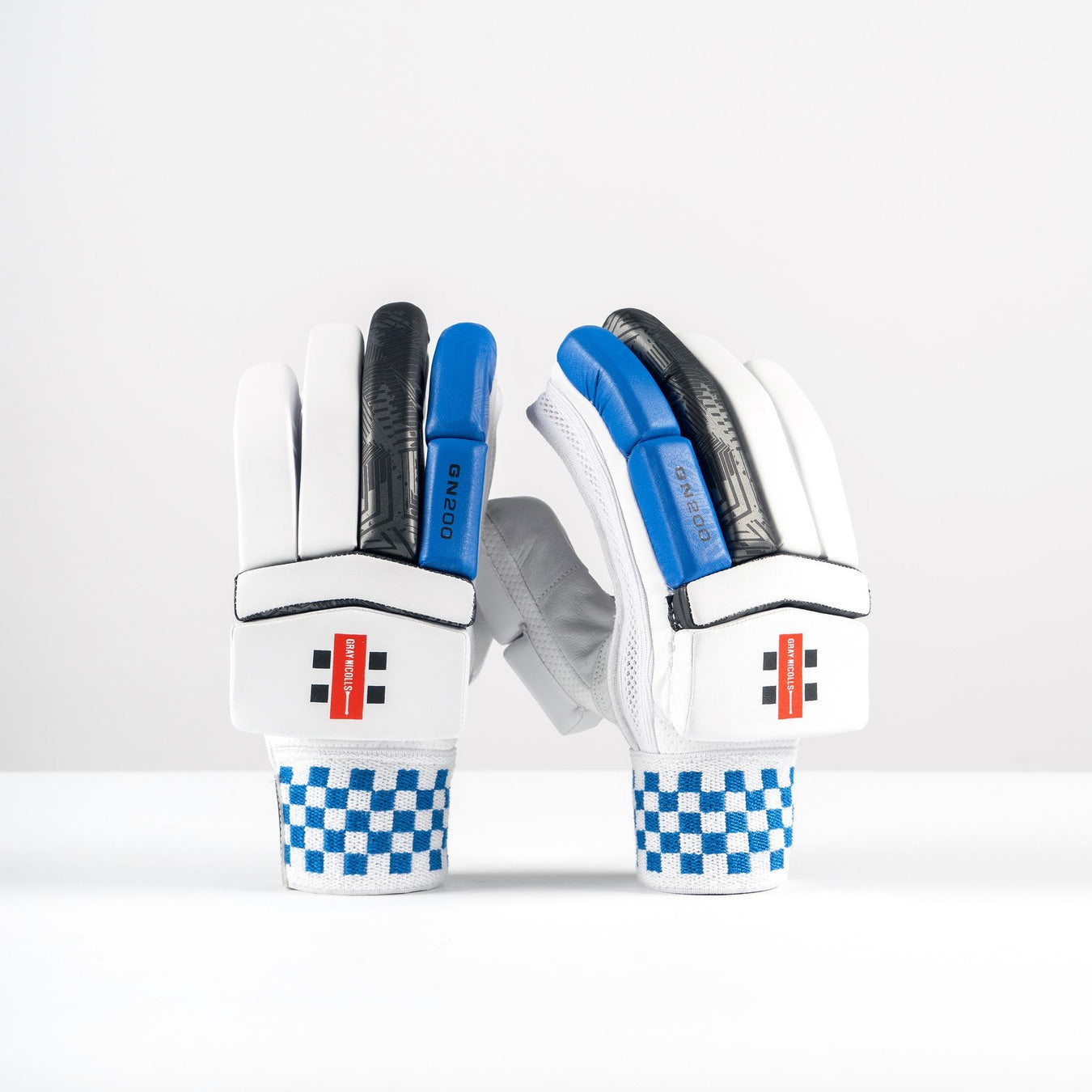 The Gray Nicolls GN200X Batting Gloves 2026 are lightweight cricket gloves with blue and black accents, checkerboard-patterned cuffs, and a red wrist label, shown upright against a plain white background.