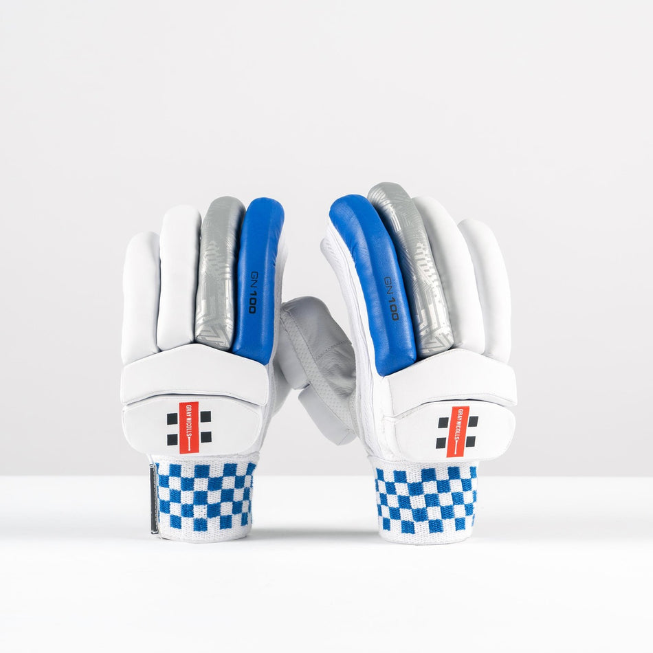 Gray Nicolls GN100X Batting Gloves 2026: white club cricket gloves with blue, gray, and silver finger padding, red Gray Nicolls branding on the wrist straps, and blue-and-white checkered cuffs, shown upright on a plain white background.