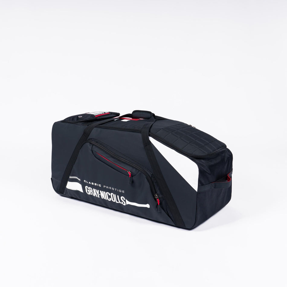 The Gray Nicolls Classic Prestige Wheelie 2026 is a large black and gray kit bag with white accents, GRAY-NICOLLS branding, multiple zippered compartments, and a shoe pocket, shown against a plain white background.