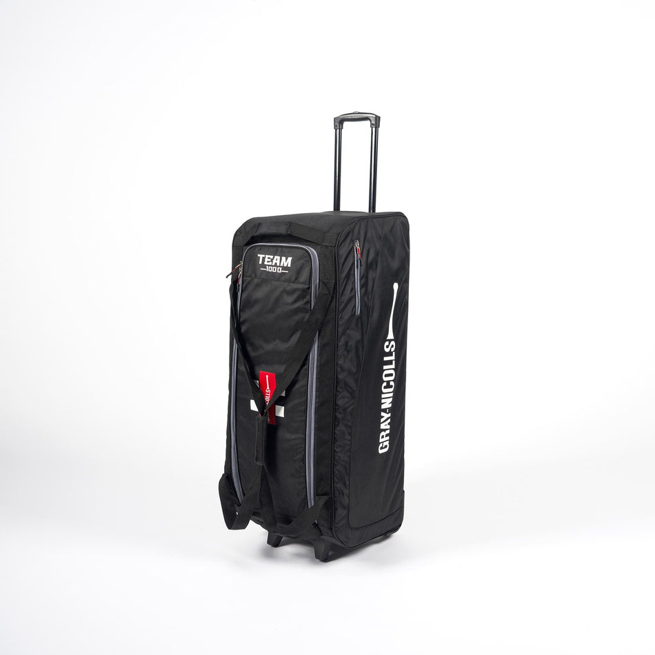 The Gray Nicolls Team 1000 Wheelie Bag 2026, in large black, stands upright on a white background with a retractable handle, multiple pockets, and the Gray Nicolls brand name and logo printed in white on the side.