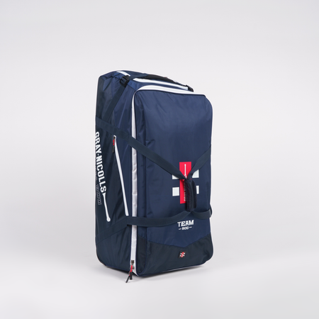The Gray Nicolls Team 800 Wheelie—a large navy blue sports duffle with white zippers, red tag, and bold white branding—offers huge storage and a heavy-duty design. It stands upright on a plain white background.