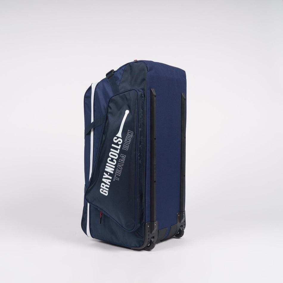 A large navy blue Gray Nicolls Team 800 Wheelie heavy-duty bag with huge storage and a side pocket, featuring the text GRAY NICOLLS TEAM 800 and a white cricket bat graphic, stands upright against a plain white background.