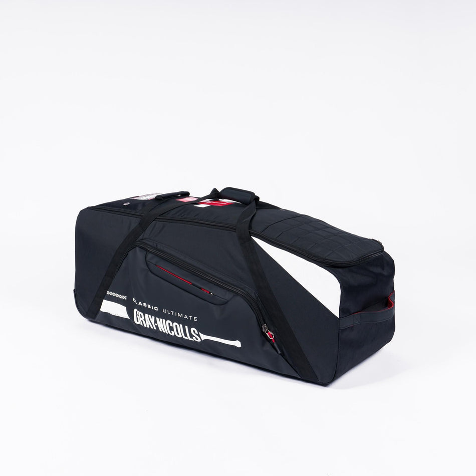 The Gray Nicolls Classic Ultimate Wheelie 2026 is a large black sports duffel with white accents, side pockets, and black handles. Featuring Gray Nicolls branding and a bat graphic, this wheelie bag is shown on a plain white background.