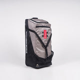 The Gray Nicolls Team 400 Wheelie is a large black/silver sports bag with deluxe wheels, black handles, and a red/white logo tag. The “Gray Nicolls” brand is visible on the side. It has a spacious main compartment and stands upright on a white background.