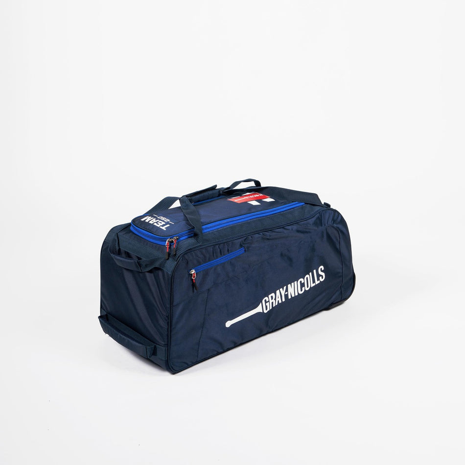 The Gray Nicolls Team 250 Wheelie Bag 2026, in Navy/Royal, features multiple zippered compartments, handles, a shoulder strap, and wheels—ideal as a cricket kit bag—shown on a plain white background.
