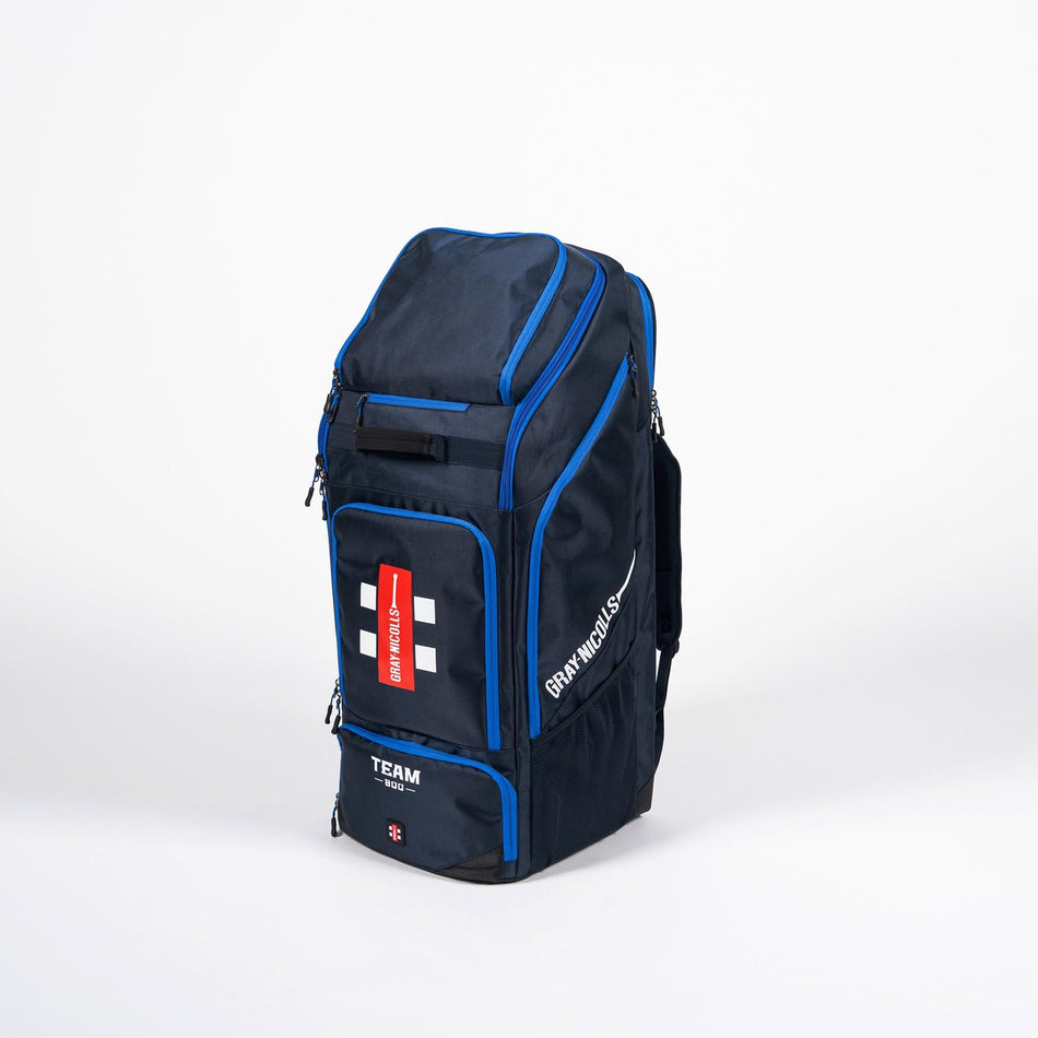 The Gray Nicolls Team 800 Duffle Bag 2026 is a large navy duffle with blue accents, multiple zippered compartments, a shoe pocket, and a red and white label on the front. It offers ample storage and stands upright on a plain white background.
