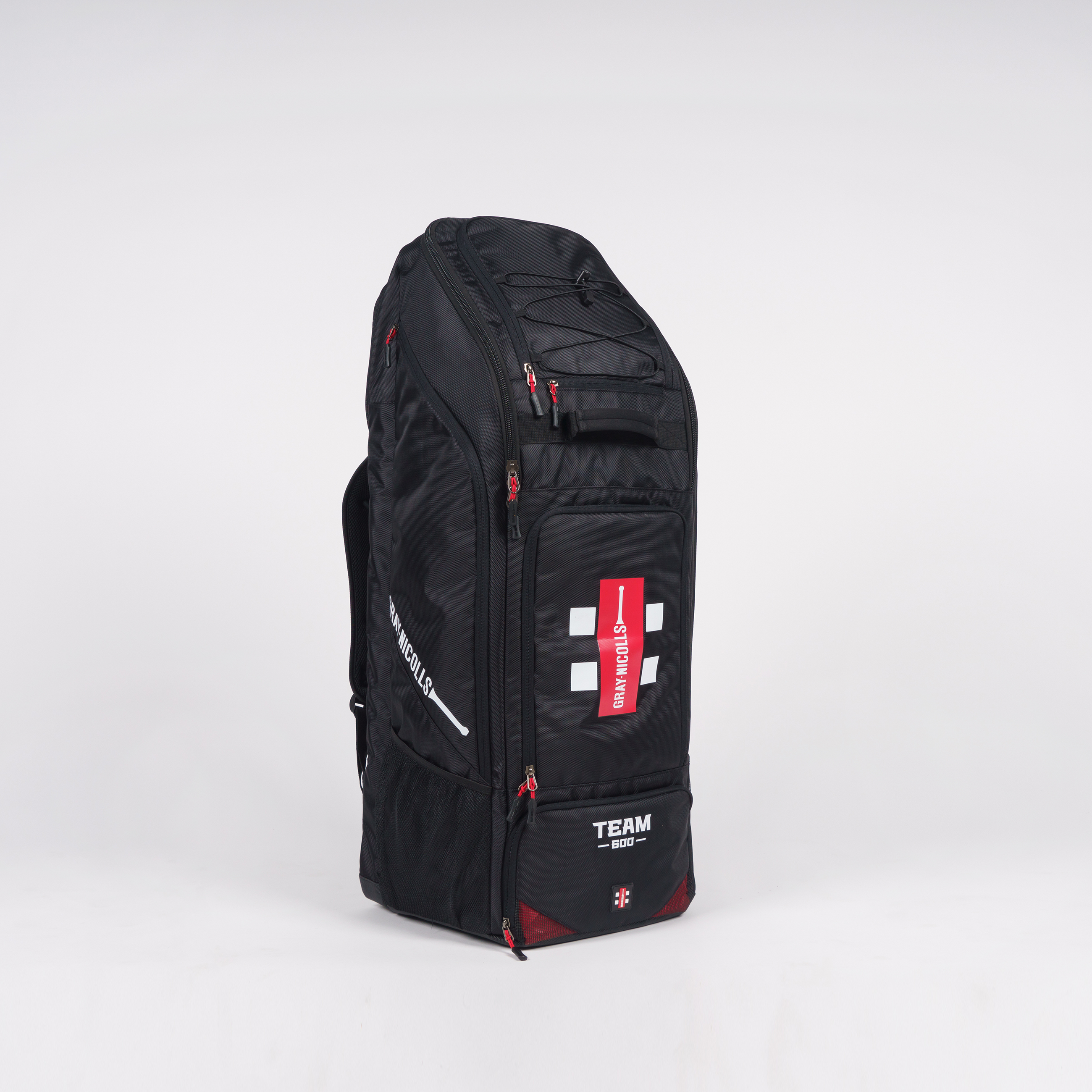 The Gray Nicolls Team 600 Duffle Bag 2026 is a large black sports backpack with red zippers, helmet and shoe pockets, side handles, a separate bat pocket, and a white “TEAM” and “SOCKS+TAPE” cross logo on the front, standing upright on a white background.