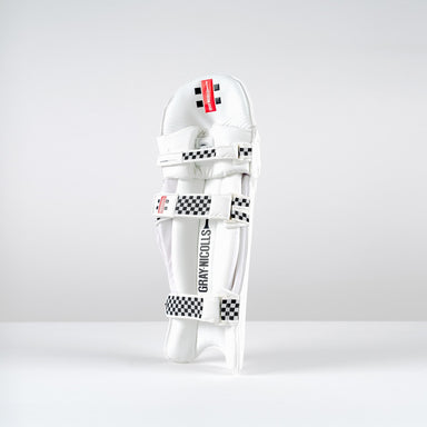 A Gray Nicolls Classic Players Edition Batting Pad 2026 stands upright on a white surface, featuring black-and-white checkered straps, a red label, and lightweight HDF multilayer protection against a plain light gray background.