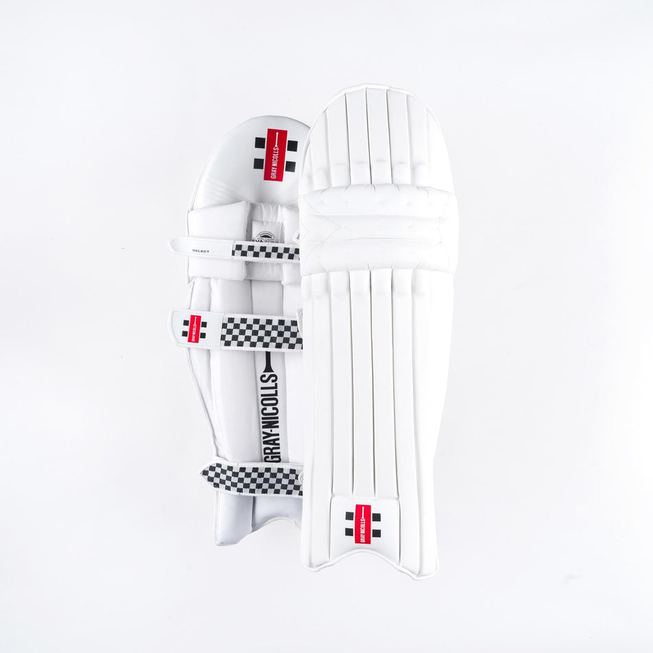 Two Gray Nicolls Classic Select Batting Pads 2026 in white are shown: one displays the front with vertical padding, while the other shows the back with straps and a checkered design, both featuring classic black and red branding.