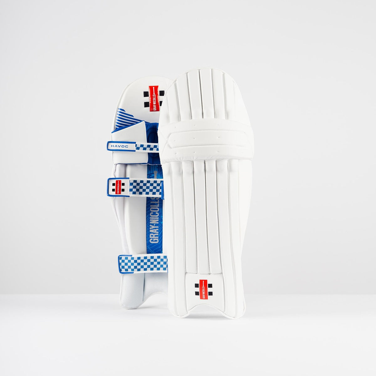 A pair of Gray Nicolls Havoc 1.0 Batting Pads 2026, known for lightweight protection, feature blue and white checkered straps with red, black, and white branding, standing upright against a plain white background.