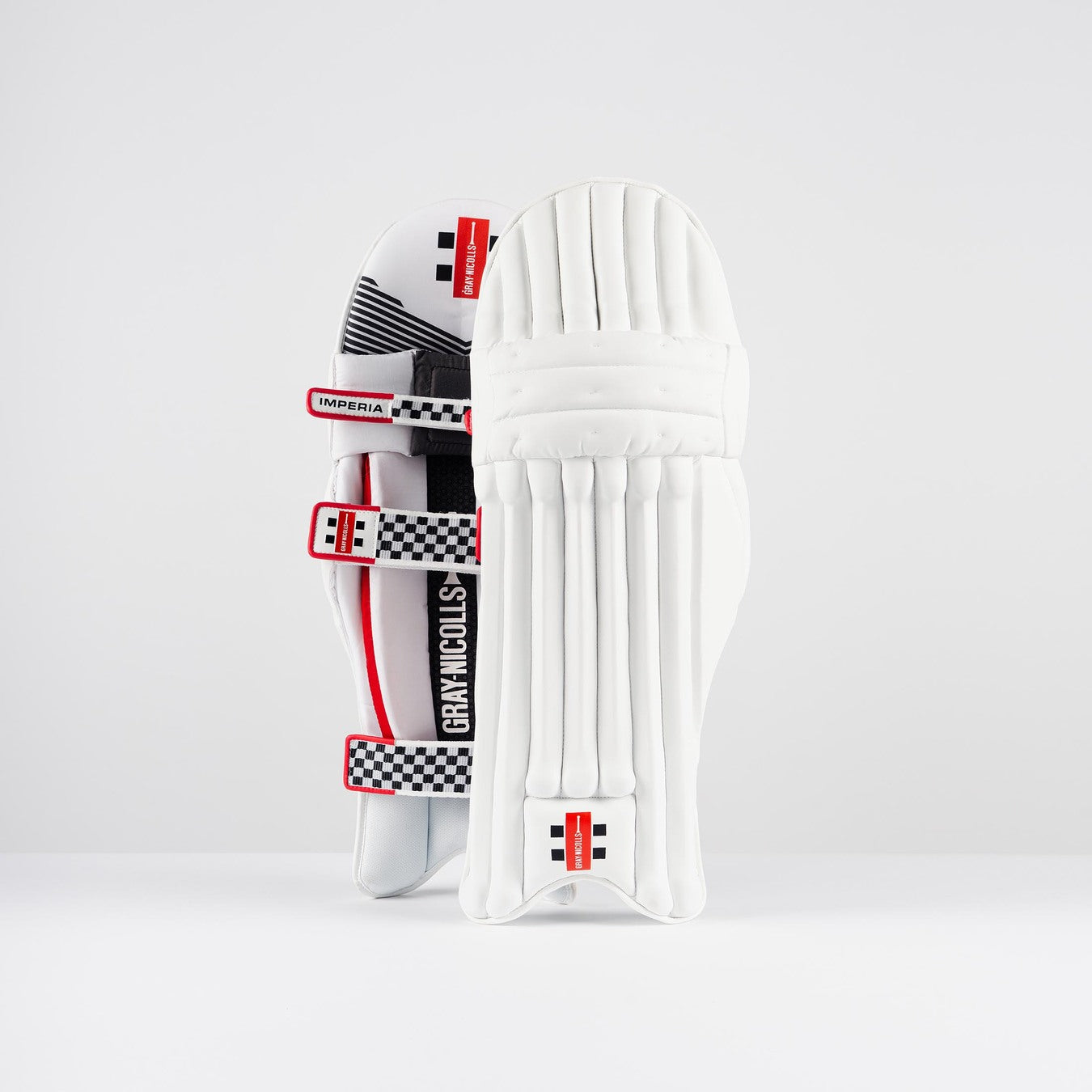 A pair of Gray Nicolls Imperia 1.0 Batting Pads 2026 in white with red and black checkered straps, offering high-impact resistance and superior cricket protection, featuring the iconic Gray Nicolls branding, upright against a plain white background.