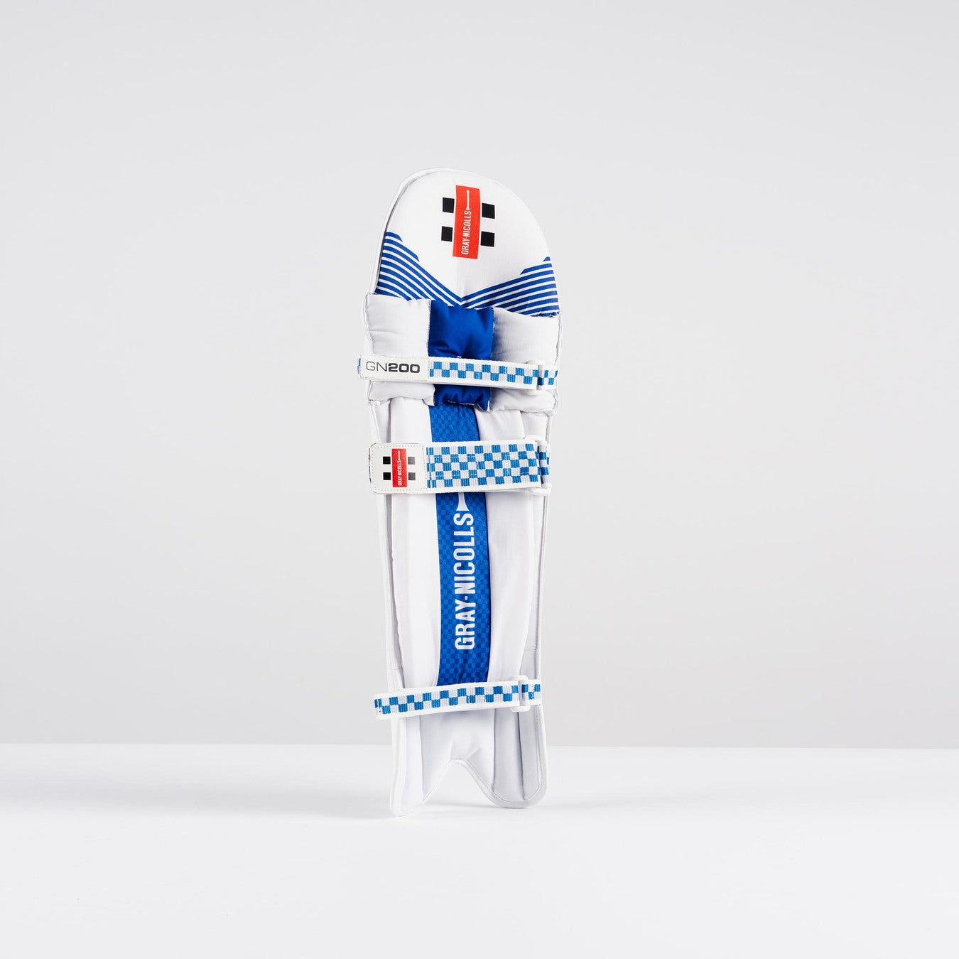 The Gray Nicolls GN200X Batting Pads 2026 feature a white finish with blue accents, checkered blue and white straps, and a red label—perfect club-level cricket gear for dependable protection against fast bowling.
