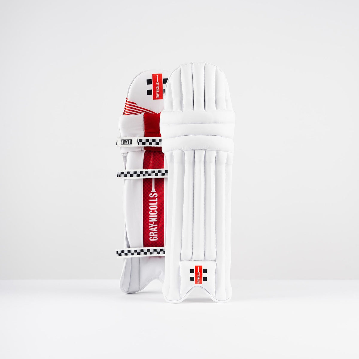 The Gray Nicolls Power X Batting Pads 2026 feature a white design with red and black accents, showcasing the iconic brand logo. One lightweight pad is shown front-facing, while the other displays the back straps for cricket protection.