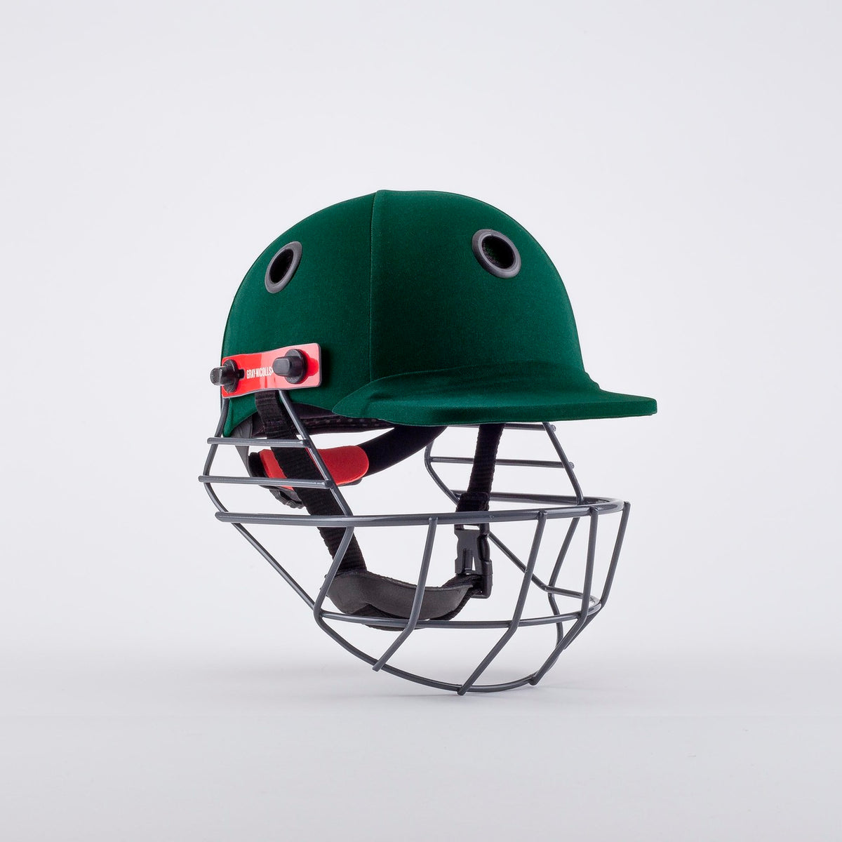 The Gray Nicolls Elite Junior Helmet in green features a metal face guard, black ventilation holes, and adjustable straps. Perfect for young cricketers starting hardball cricket, shown against a white background.