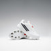 A pair of Gray Nicolls Revo Pro 3 Cricket Spikes is displayed against a gradient background, one upright and one leaning to highlight the metal spikes, featuring lightweight design with black stripes and red accents.