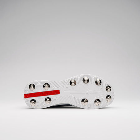 The image shows the underside of the Gray Nicolls Revo Pro 3 Cricket Spikes, a white lightweight cricket shoe with metal studs and a red REMOVABLE section near the heel, ideal for test level cricket. Brand: Gray Nicolls.