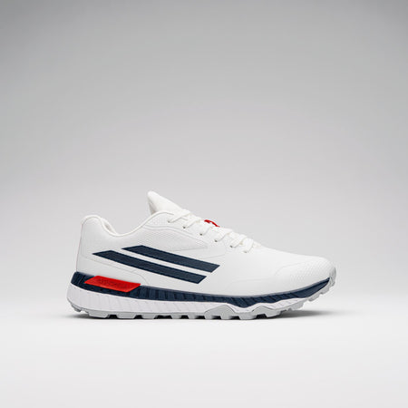 The Gray Nicolls Revo Pro 3 Cricket Batting Shoe by Gray Nicolls is a white athletic shoe with dark blue stripes, red heel accent, and textured white sole, featuring a lightweight design and shown on a plain light gray background.