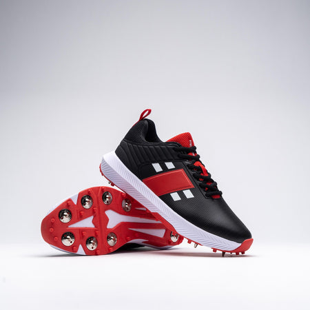 The Gray Nicolls Players 3.0 Black Cricket Spike features black, red, and white athletic styling with metal spikes and a speedbase outsole for traction. One shoe stands upright; the other is on its side showing the spiked sole.