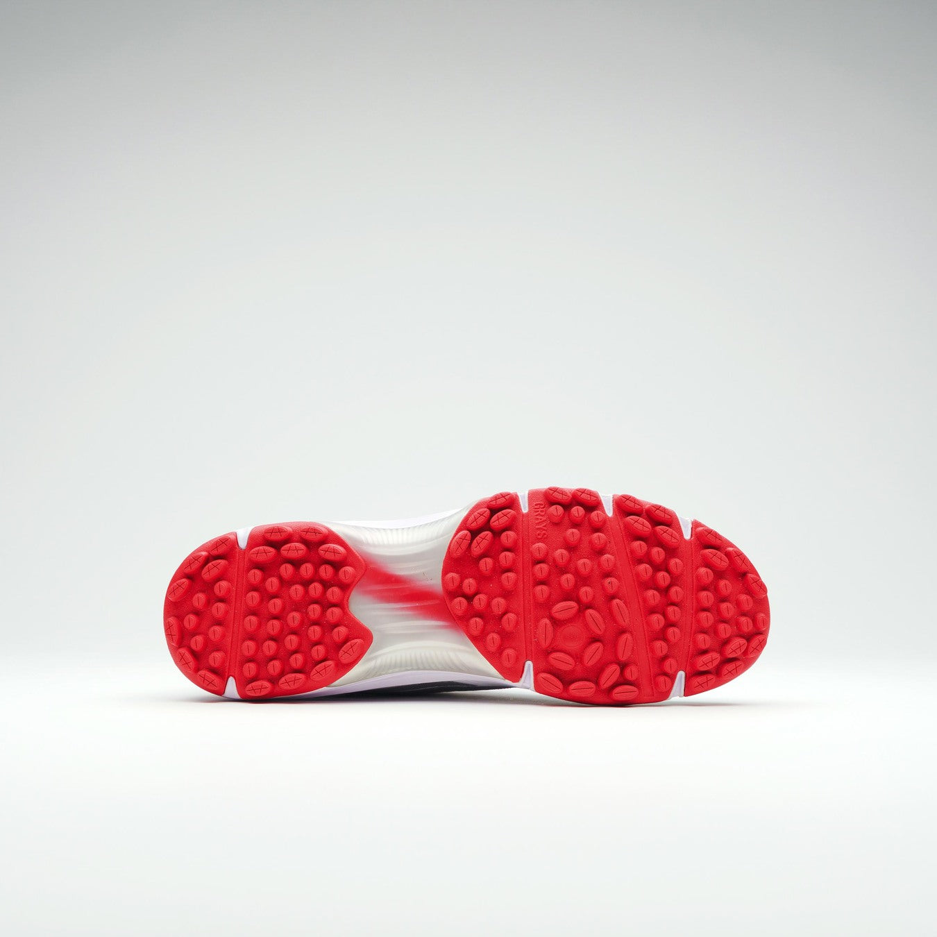 A close-up of the Gray Nicolls Velocity 5.0 Rubber Sole Cricket Shoe's textured red rubber outsole with circular grips and an EVA midsole, photographed against a plain light gray background.