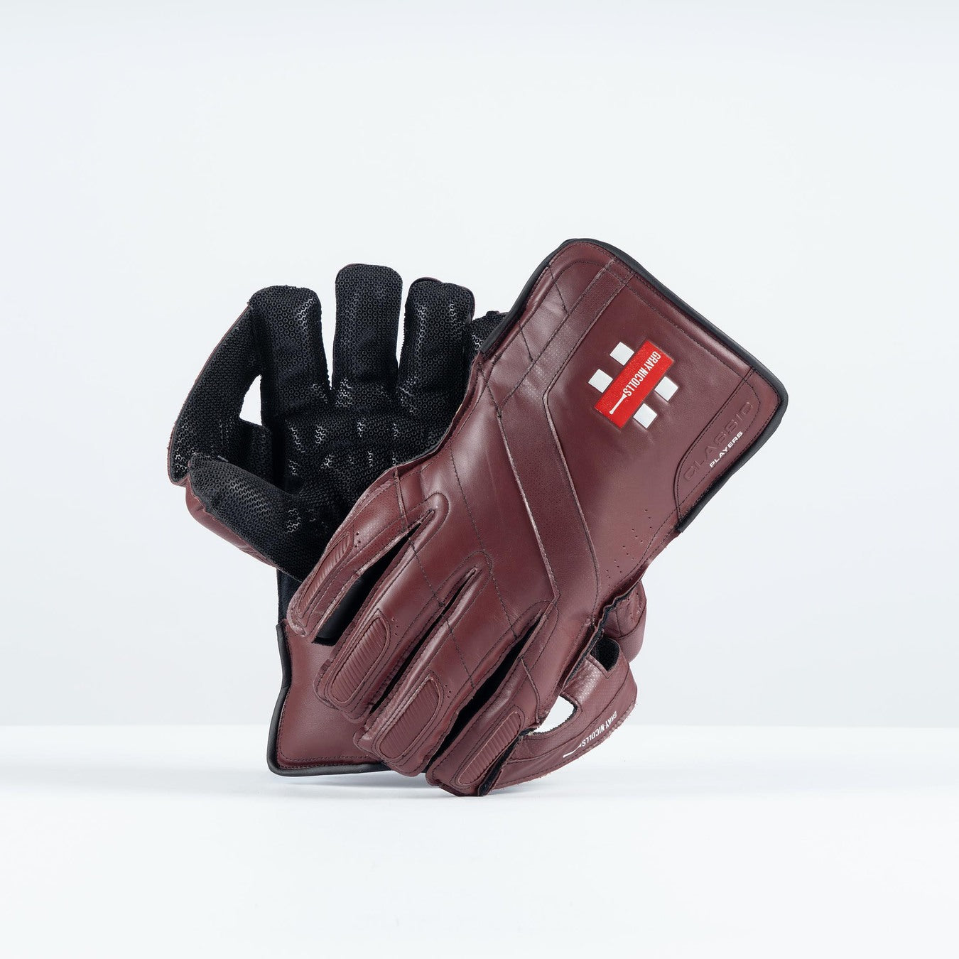 The Gray Nicolls Classic Players Edition WK Gloves 2026, in maroon, are displayed upright against a plain white background, featuring premium leather and octopus grip padding with a red rectangular wrist logo.